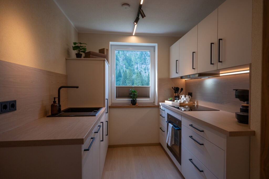 Moderne mattschwarze Küche der Ferienwohnung Murmale mit Holz-Arbeitsplatte, Kaffeemaschine und Backofen