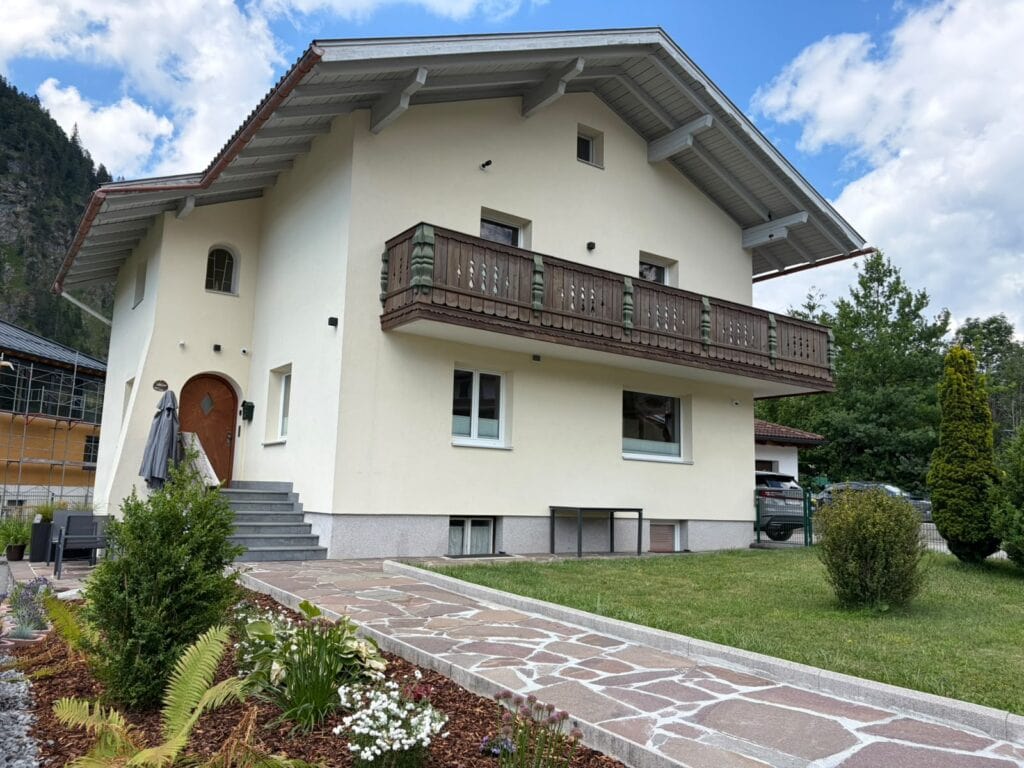 Außenansicht des Hauses Schmiede25 mit Balkon, Blumenbeet und Garten.